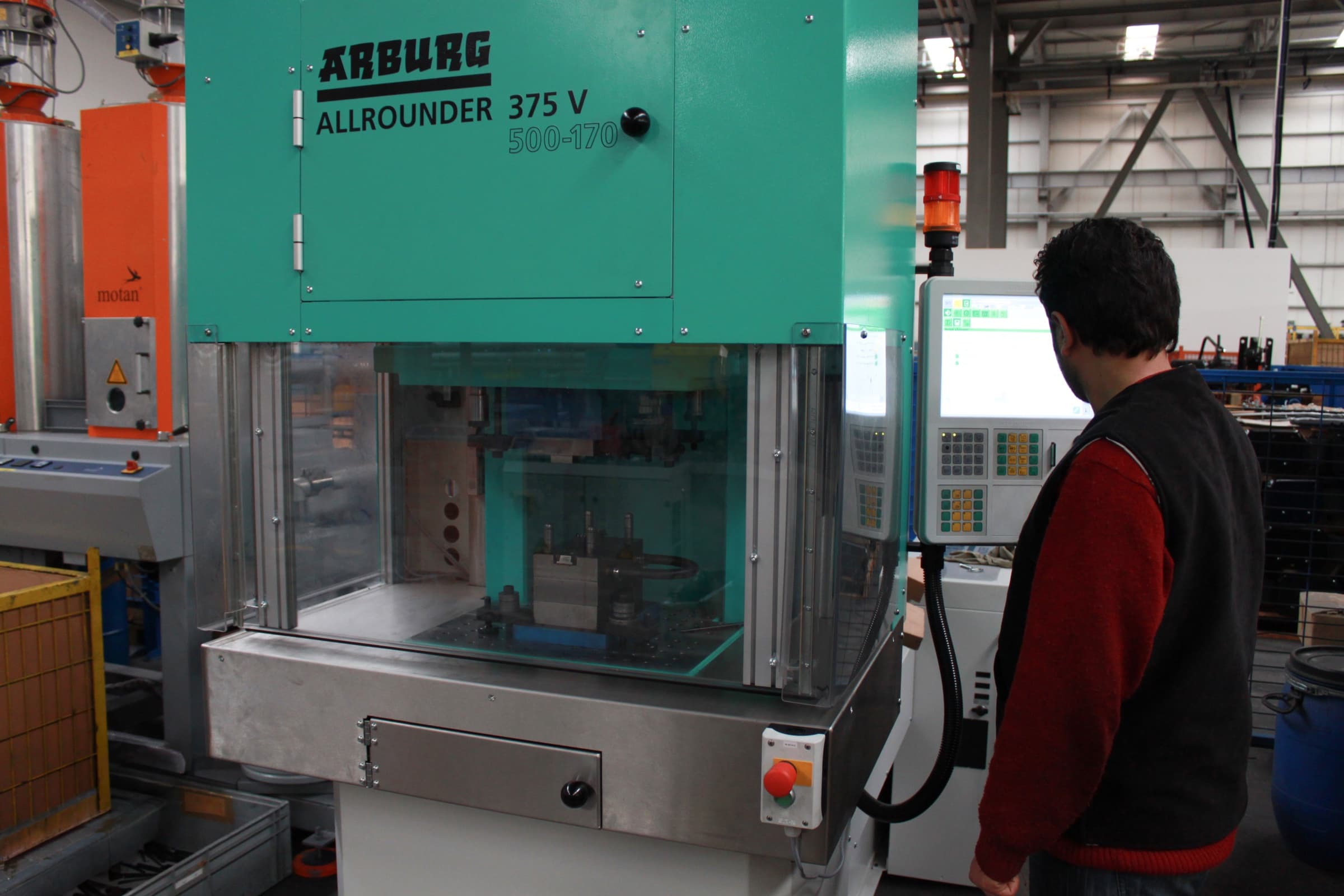 Operator running a vertical injection molding machine for prototype parts at Makersan